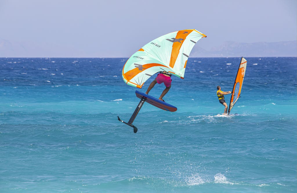 A man windsurfing in the ocean with a sail